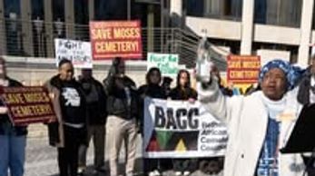 Group protesting to save Moses Cemetery with signs and banners.