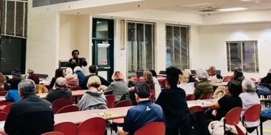 A diverse group attending a community meeting in a large room.