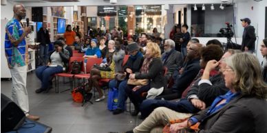 Speaker addressing a diverse audience in a community event.
