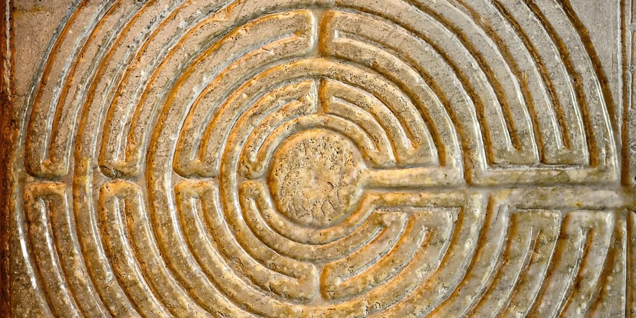 Close-up of an ancient stone labyrinth carving with concentric circular paths.