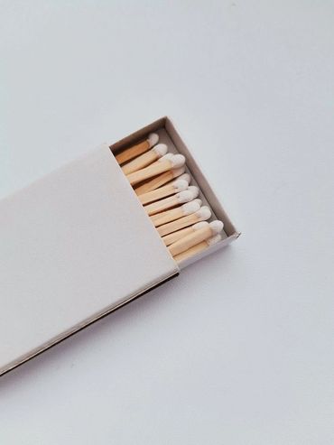 A white matchbox partially open with white-tipped matches inside.