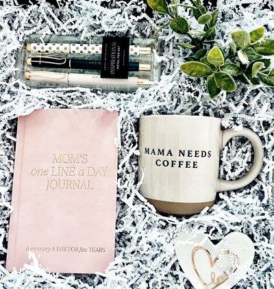 A cozy gift set with a journal, coffee mug, pens, and decorative heart.