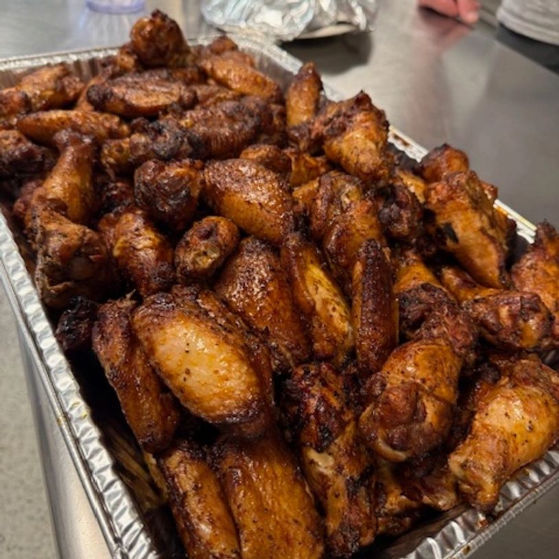Tray filled with seasoned and cooked chicken wings on a kitchen counter.
