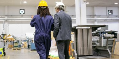 Engineer and manager discuss plans in a factory setting.