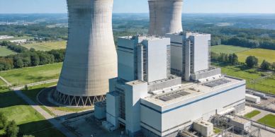 A nuclear power plant with cooling towers in a green landscape.