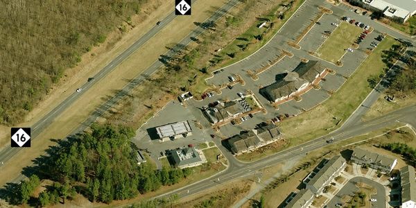 Aerial view of a commercial area with buildings, parking lots, and a highway marked 16.