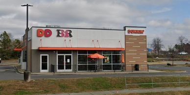 A Dunkin' Donuts store with partially missing signage under a cloudy sky.