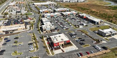 Aerial view of a shopping center with parking lots and various stores.