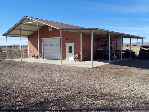 A large barn with a covered porch under a clear blue sky.
