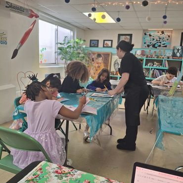 People engaged in a group art activity at a decorated table in a colorful room.