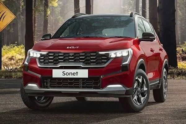 Red Kia Sonet SUV in forest setting.