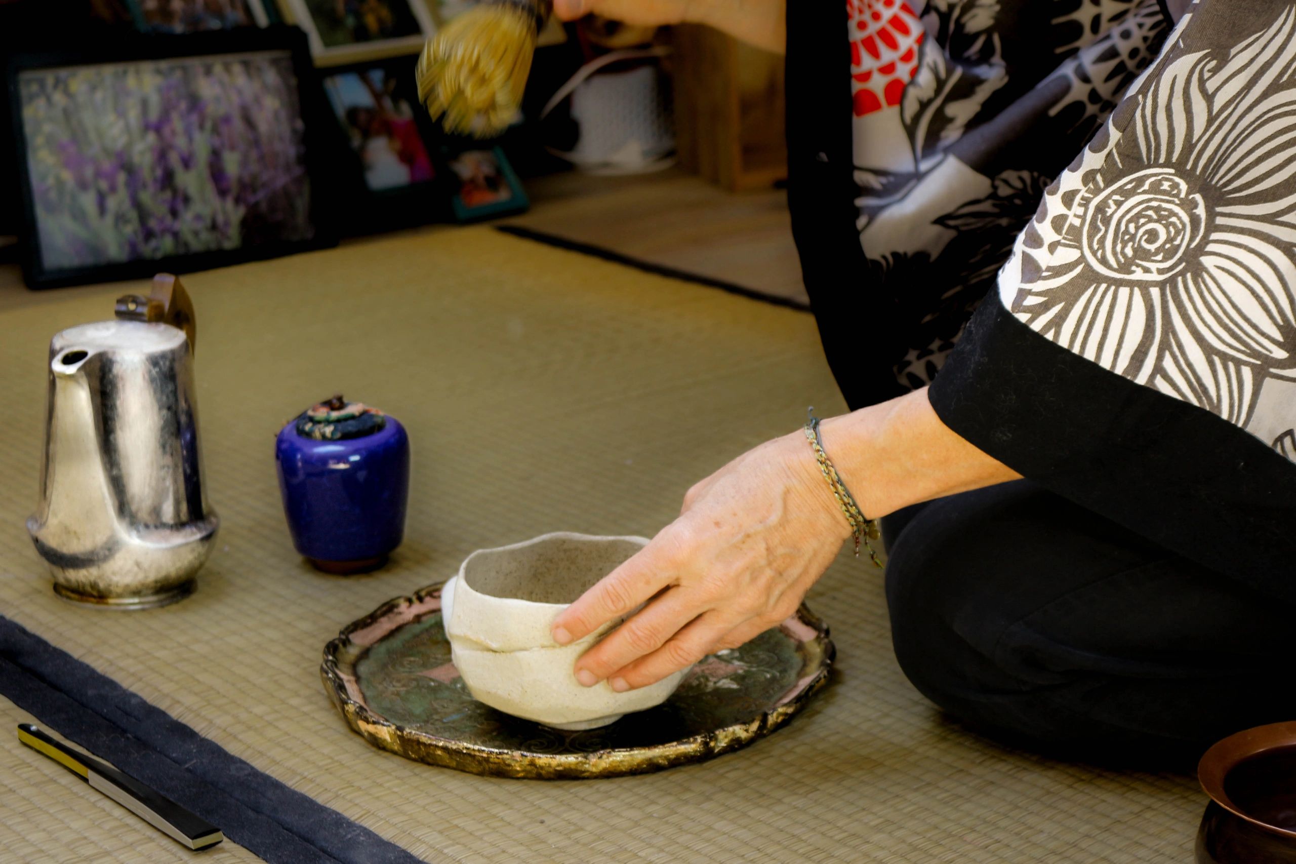 Person preparing tea in a traditional Japanese tea ceremony setting.