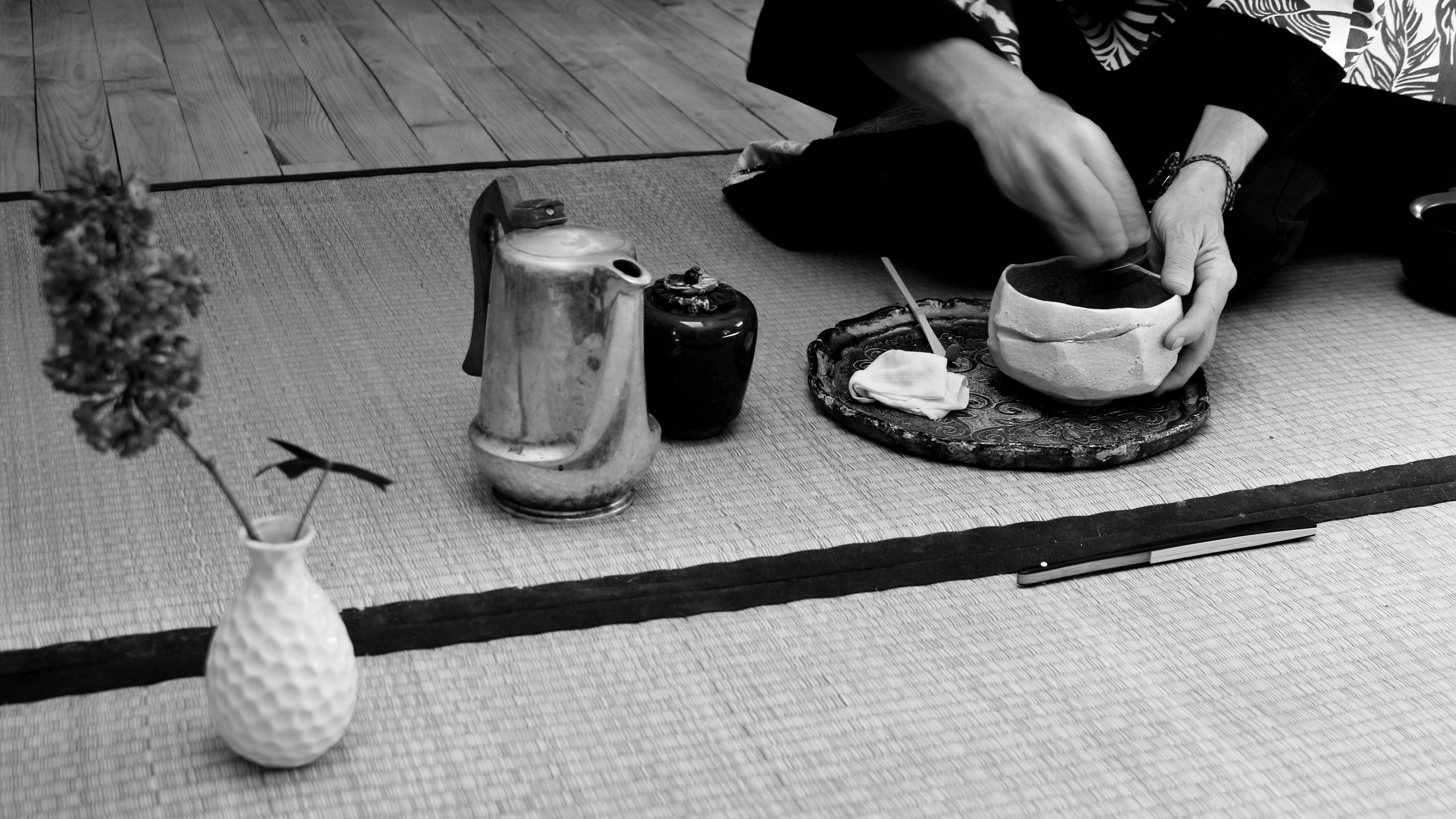 Traditional Japanese tea ceremony setup with hands preparing tea.