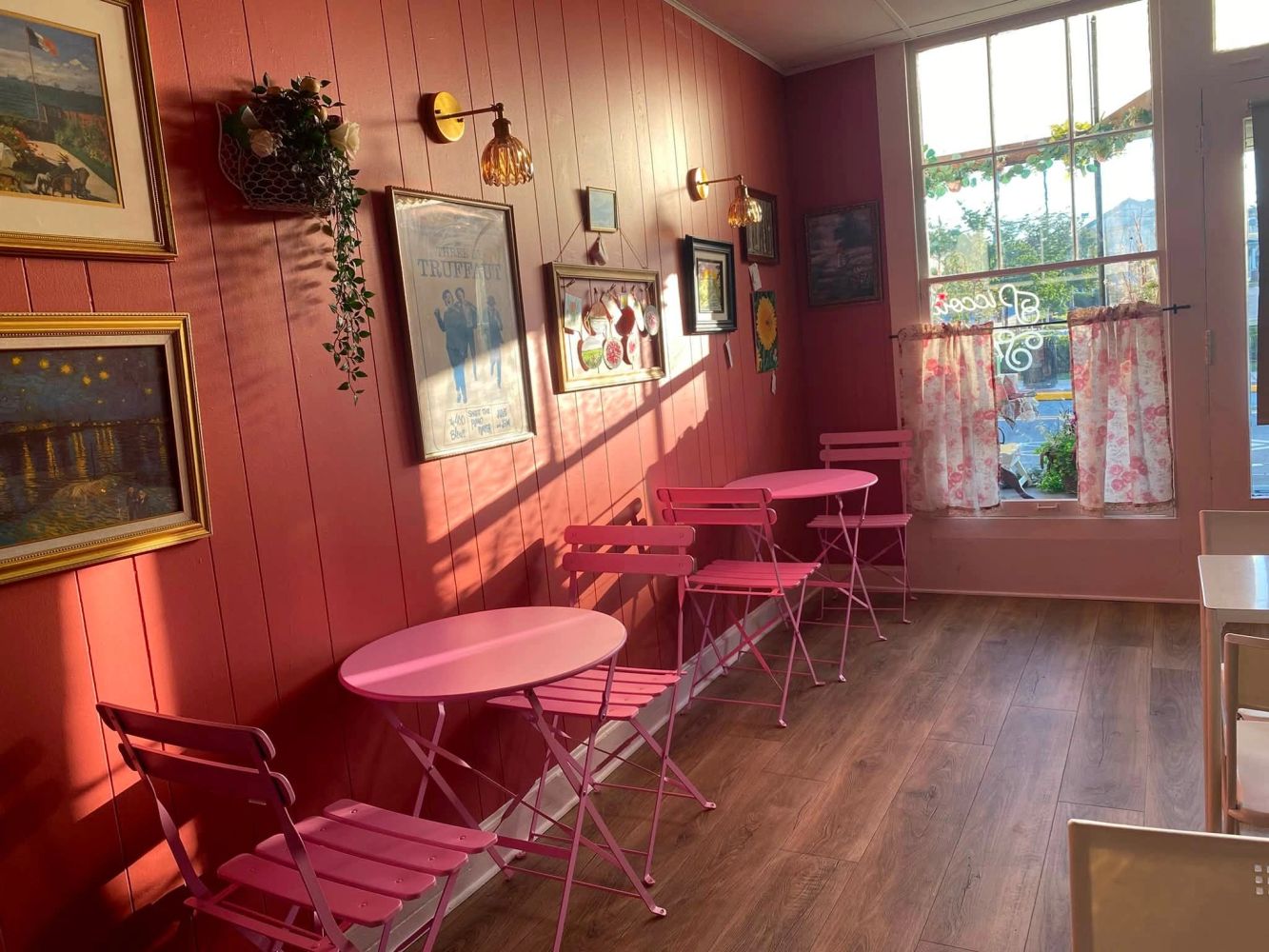 Cozy pink cafe corner with vintage wall decor and sunlight.