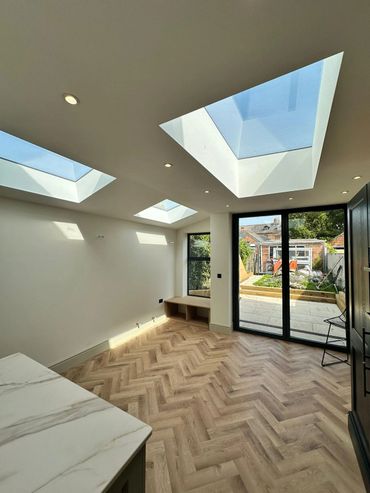 Modern room with skylights and glass doors opening to a garden.