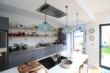 Modern kitchen with blue pendant lights and a white island.