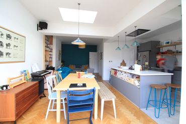 Bright, modern open-plan kitchen and dining area with colorful chairs and skylight.