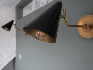 Two black and gold wall-mounted lamps on a gray wall.