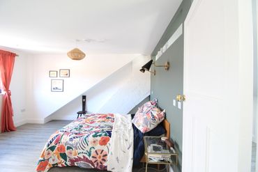 Bright bedroom with colorful bedding and modern decor under a slanted ceiling.