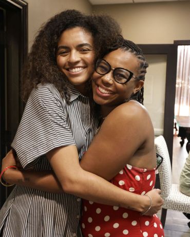 Two women hugging and smiling warmly.