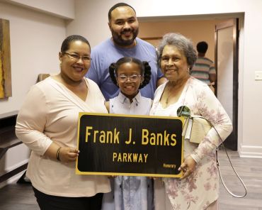 Family holding a street sign honoring Frank J. Banks.