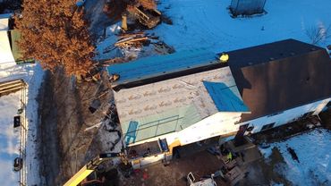 Aerial view of a house with a partially roof replacement in progress during winter.