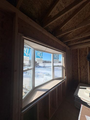 Newly installed bay window in a wooden frame under construction.