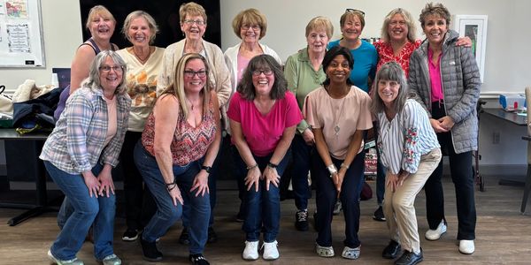 Group of women posing cheerfully indoors in casual attire.