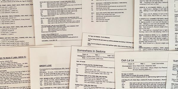 A collection of printed line dance instructions spread out on a surface.