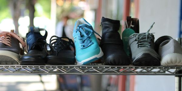 A variety of shoes lined up on a metal shelf outdoors.