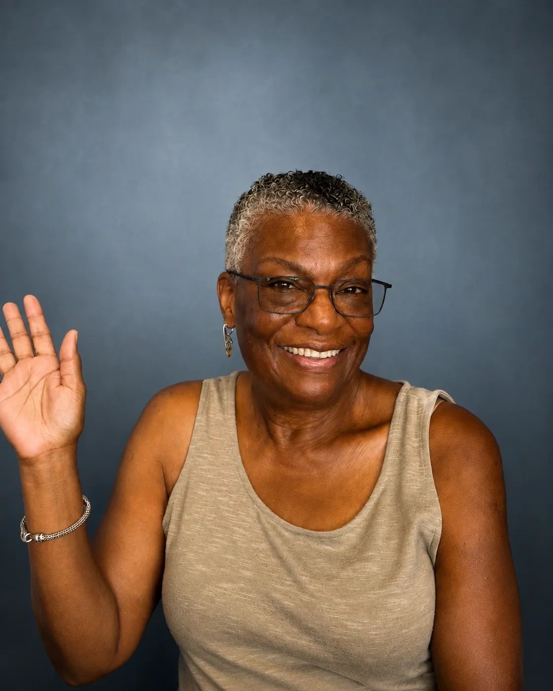 Smiling older woman waving at the camera.