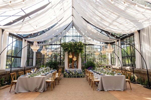 Elegant wedding reception setup in a glass greenhouse.