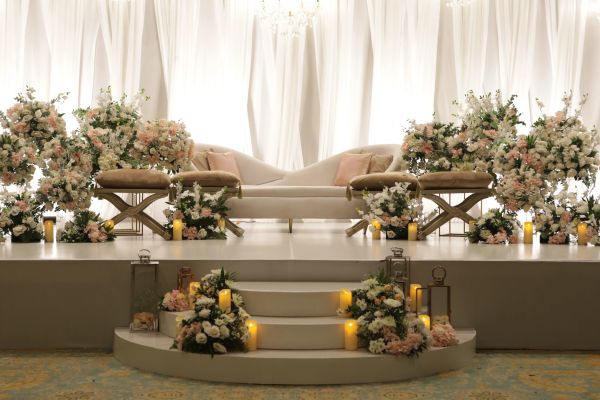 Elegant wedding stage with floral arrangements and candles.