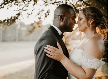 A bride and groom lovingly embrace outdoors at sunset.