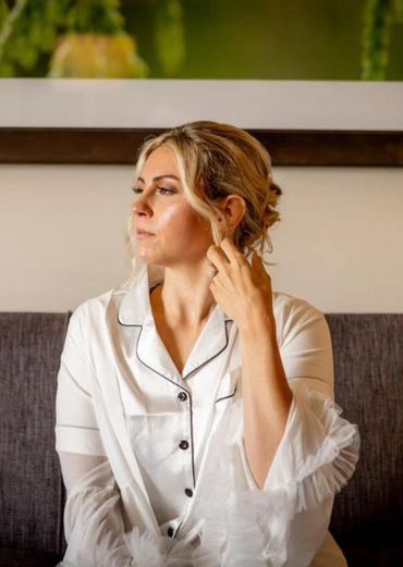 Woman in white sitting on a couch, looking contemplative.