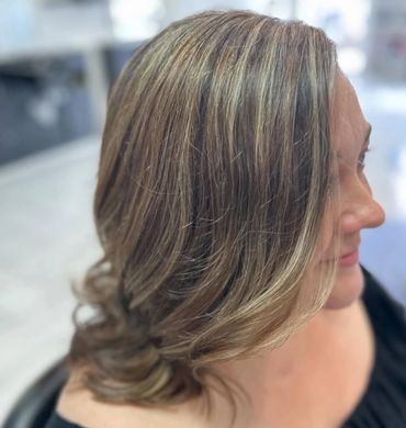 Side view of a woman with highlighted, styled medium-length hair.