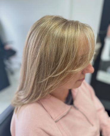 Woman with smooth, layered blonde hair and side-swept bangs.