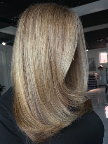 Smooth, layered blonde hair with subtle highlights styled elegantly.