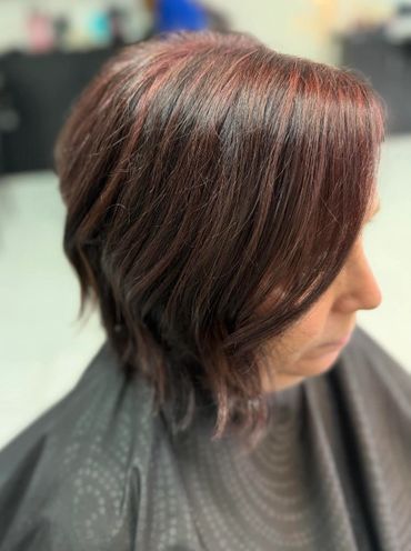 Side view of a woman with layered, reddish-brown hair.
