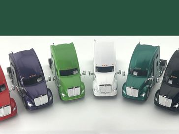 Seven colorful toy trucks lined up on a white surface.