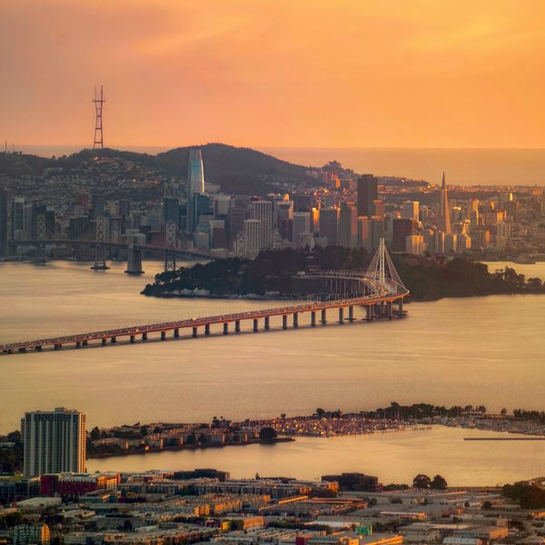 Golden light bounding off the Bay and skyscrapers in the San Francisco skyline during sunset. 