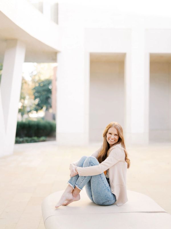 Smiling woman sitting barefoot outdoors.