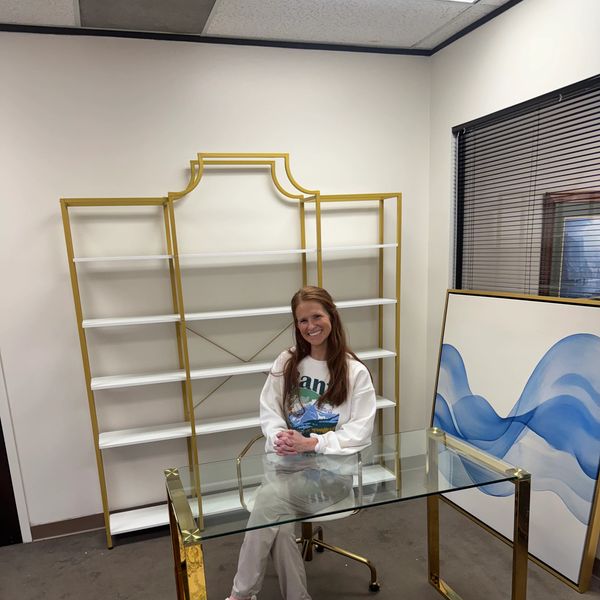 A woman sitting at a glass desk in a modern office.