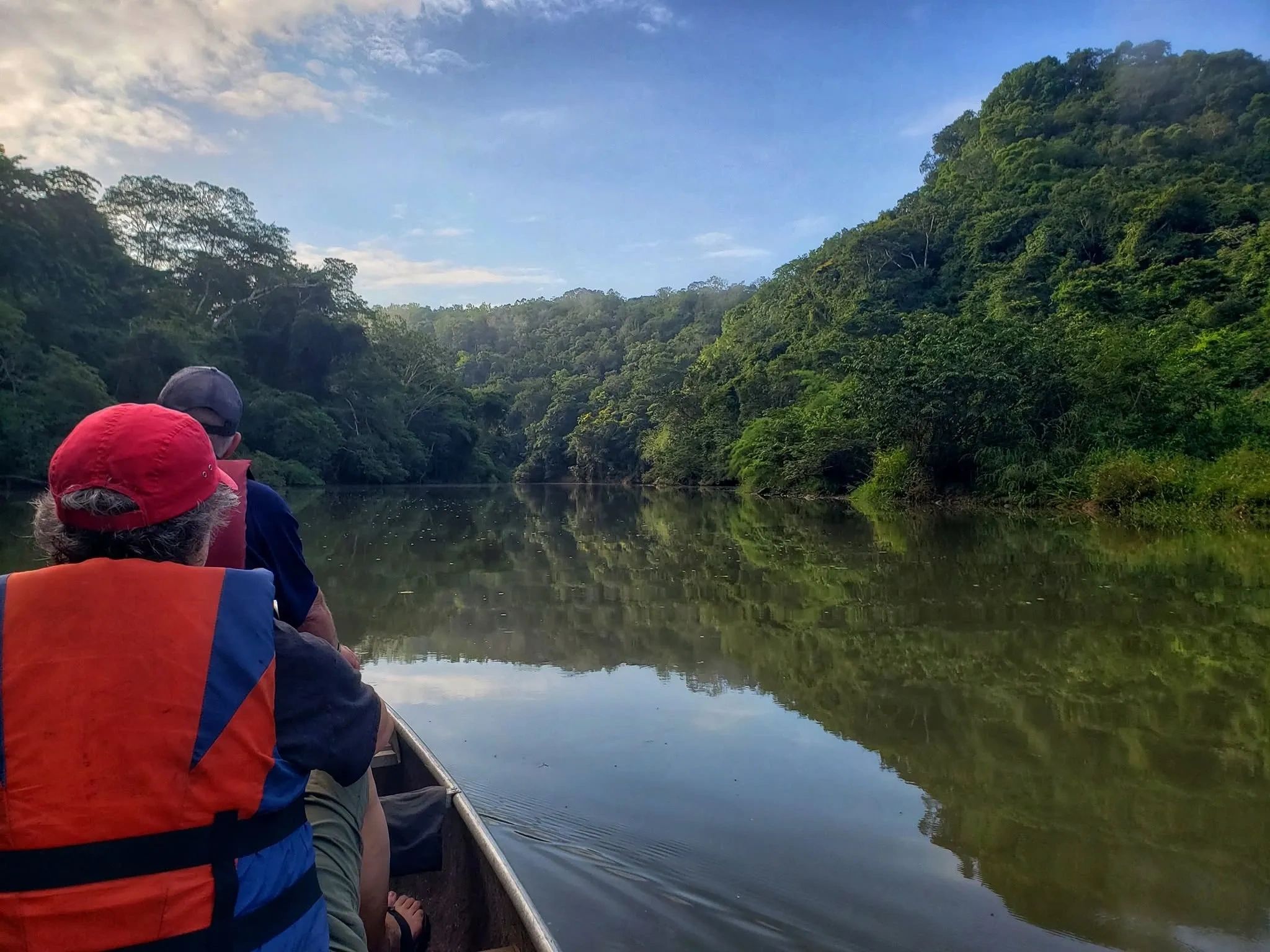 Two people on a boat trip in a lush green river.