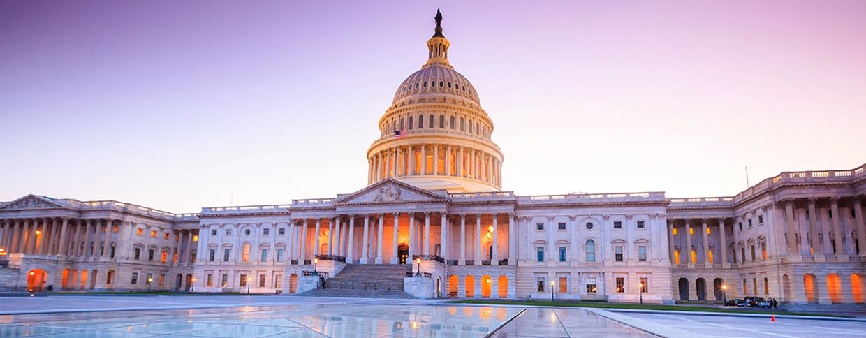 The illuminated United States Capitol at dusk with a clear sky.