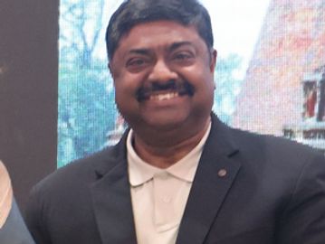 A smiling man in a black blazer and white shirt.