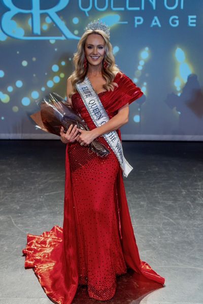 Woman in a red gown with a crown and sash holding flowers on stage.