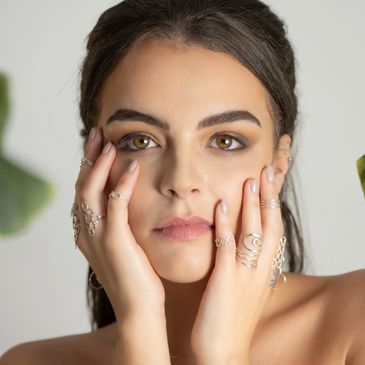 Woman with rings on her fingers touching her face.