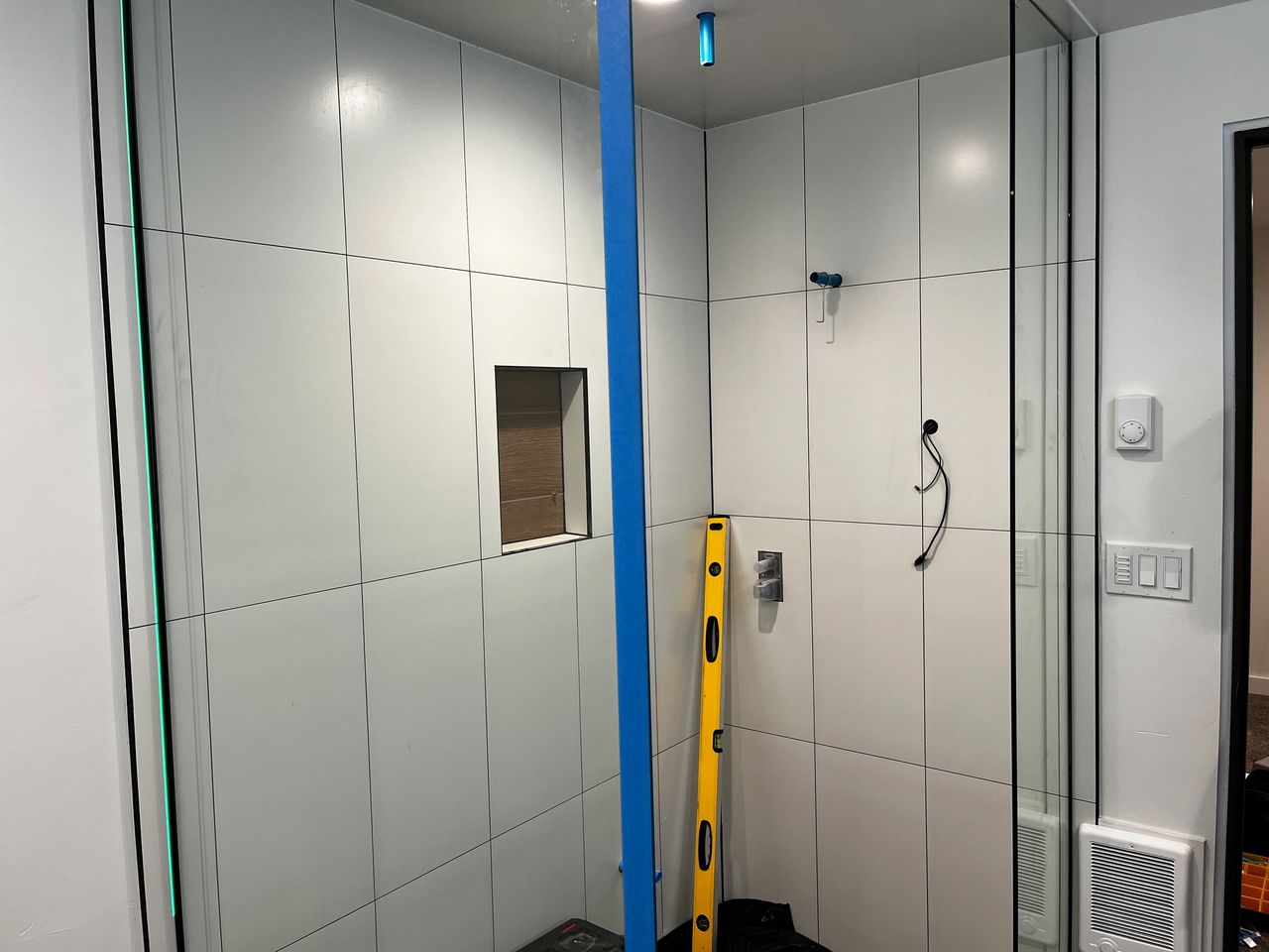 The custom glass shower enclosure halfway installed