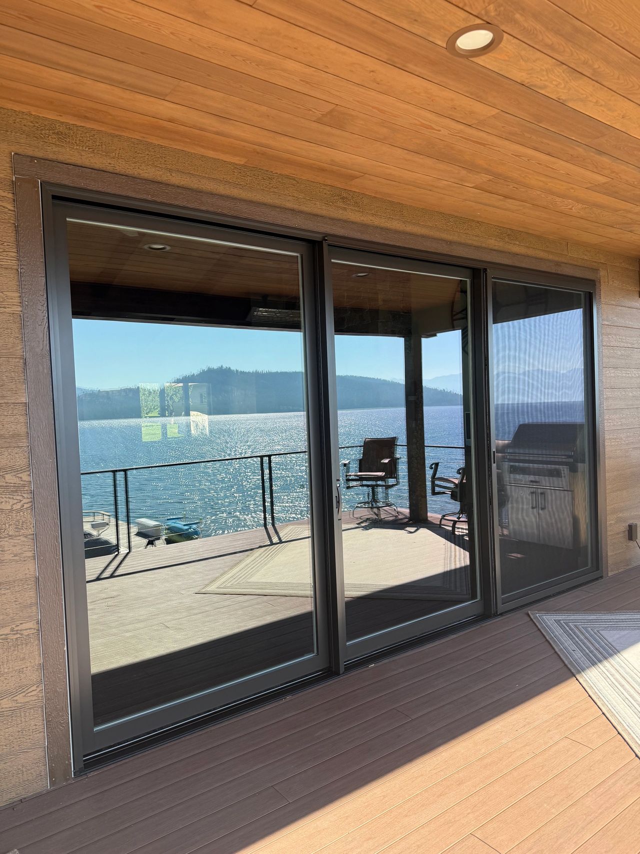 The exterior view of upper the Pella Lifestyle triple sliding door Precision Glass installed in Lakeside Montana. It has a brown exterior cladding metal